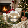Double-sided German travel ornament resting beside holiday gifts near a warm brick fireplace.