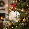 Coastal lighthouse ornament hanging among glowing lights on a Christmas tree branch.