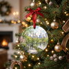 Ceramic New York holiday ornament hanging from an evergreen tree branch beside glowing Christmas lights.