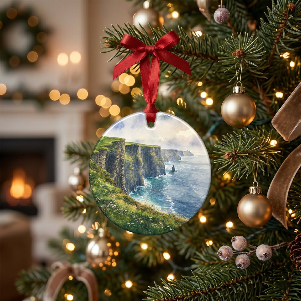 Irish coastal watercolor holiday keepsake hanging on an illuminated Christmas tree branch.