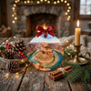 Festive desert holiday ornament styled on a rustic table alongside pinecones and a candle.