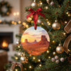Ceramic Southwest desert ornament hanging from a holiday tree branch surrounded by warm festive fairy lights.