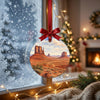 Scenic road trip ornament suspended in front of a frosty window in daytime.