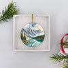 Round alpine lake souvenir ornament nestled safely inside an open white gift box ready for gifting