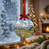 Winter mountain artwork ornament catching natural daytime sunlight while hung near a frosty window.