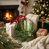 Ceramic rainforest ornament styled beside festive holiday gifts near a glowing living room fireplace.