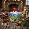 Scenic Romanian mountain ornament arranged on a tabletop beside a rustic pinecone and a warm candle.