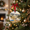 Ceramic holiday decoration hanging from an illuminated evergreen Christmas tree branch.